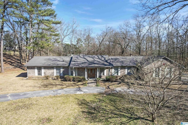 ranch-style home with brick siding, driveway, and a front lawn