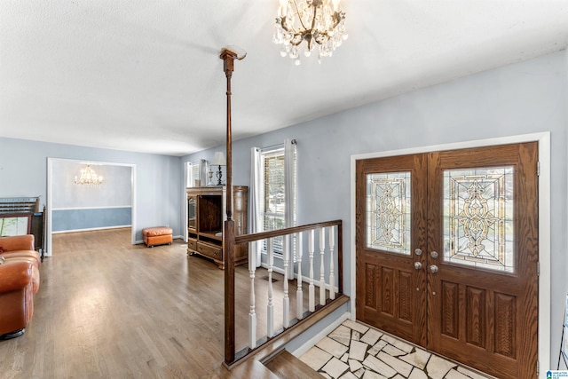 entryway with light wood-style flooring, baseboards, and a notable chandelier