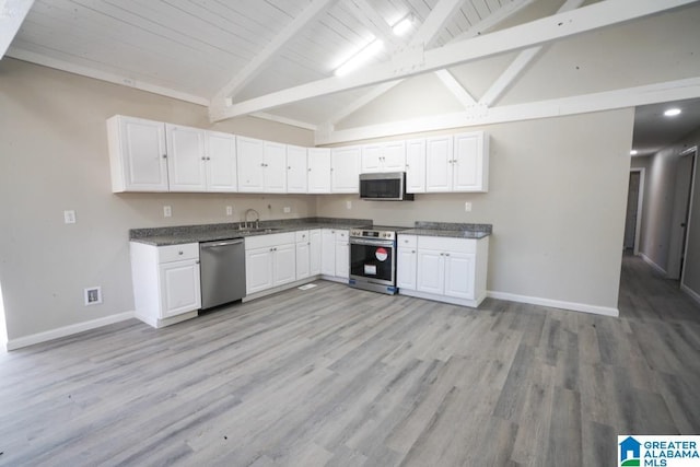 kitchen with vaulted ceiling with beams, white cabinetry, appliances with stainless steel finishes, and baseboards