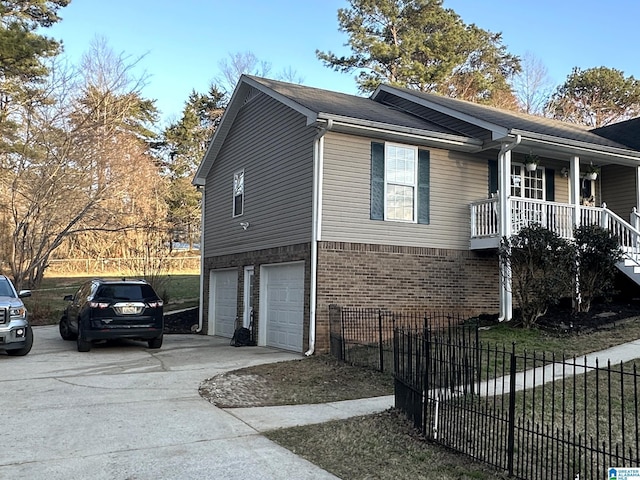 view of front of property with driveway, a garage, covered porch, fence, and brick siding