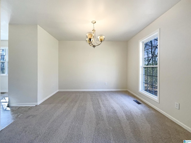 carpeted spare room with visible vents, baseboards, and an inviting chandelier