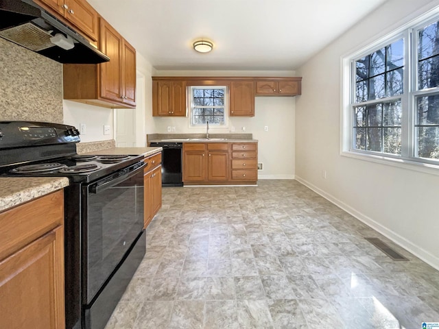 kitchen with baseboards, visible vents, under cabinet range hood, light countertops, and black appliances