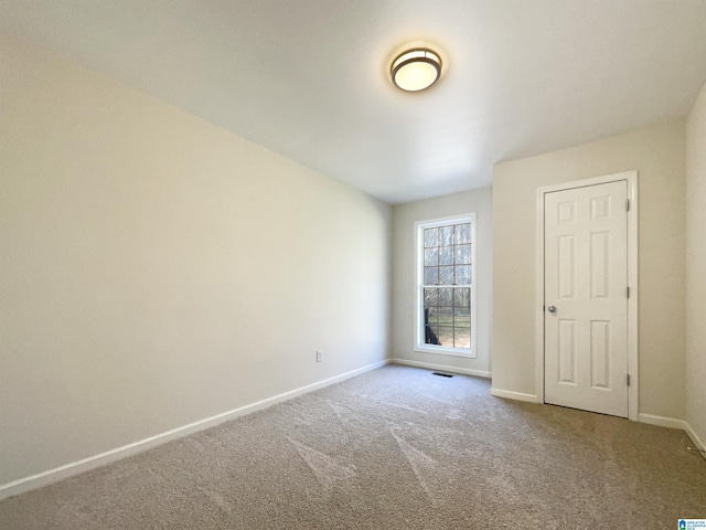 empty room with carpet, visible vents, and baseboards