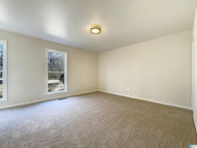 unfurnished room with carpet floors, visible vents, and baseboards