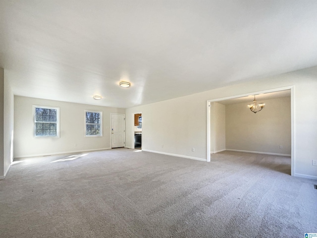 unfurnished room with a chandelier, carpet, and baseboards