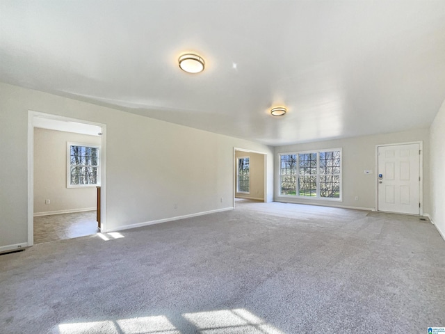 unfurnished living room featuring carpet flooring and baseboards