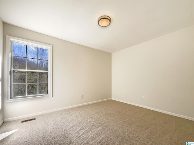 carpeted empty room with visible vents and baseboards