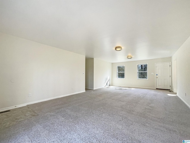 carpeted spare room with visible vents and baseboards