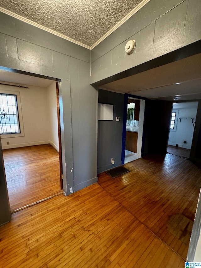 spare room featuring baseboards, hardwood / wood-style floors, visible vents, and crown molding