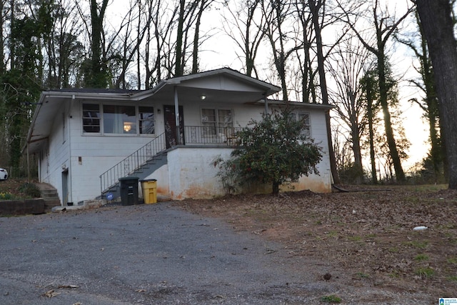 view of front of property featuring covered porch, driveway, and stairway