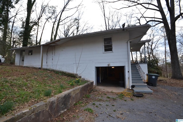 view of side of home featuring an attached garage and stairway