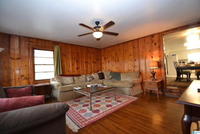 living room featuring a ceiling fan, wooden walls, and wood finished floors