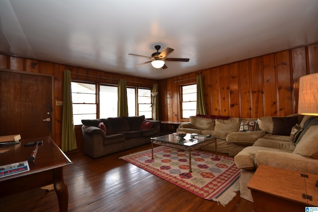 living area featuring ceiling fan, wooden walls, and wood finished floors