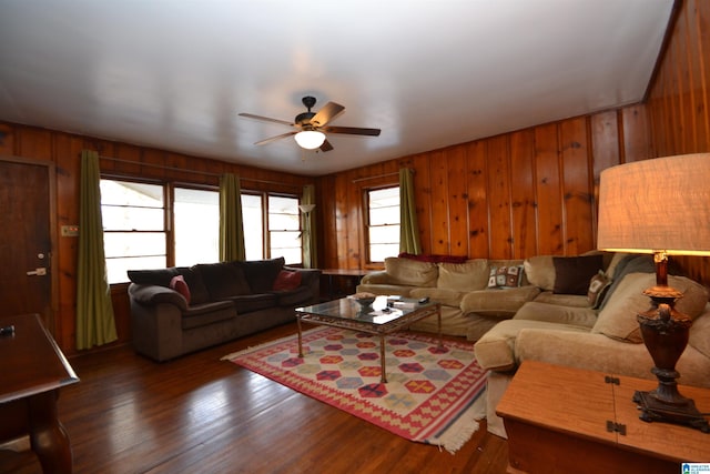 living area with wood walls, ceiling fan, and wood finished floors