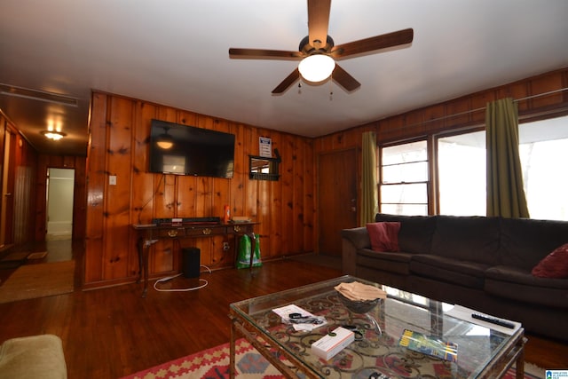 living room featuring wood walls, a ceiling fan, and wood finished floors