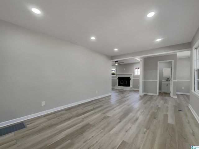 unfurnished living room with recessed lighting, a fireplace, visible vents, baseboards, and light wood-style floors