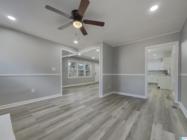 interior space featuring light wood-style floors, baseboards, a sink, and recessed lighting