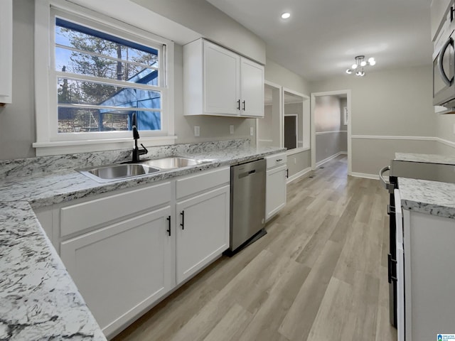 kitchen featuring appliances with stainless steel finishes, light wood-type flooring, white cabinetry, and a sink