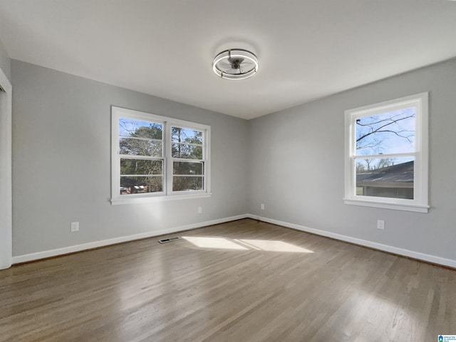 spare room with visible vents, baseboards, and wood finished floors