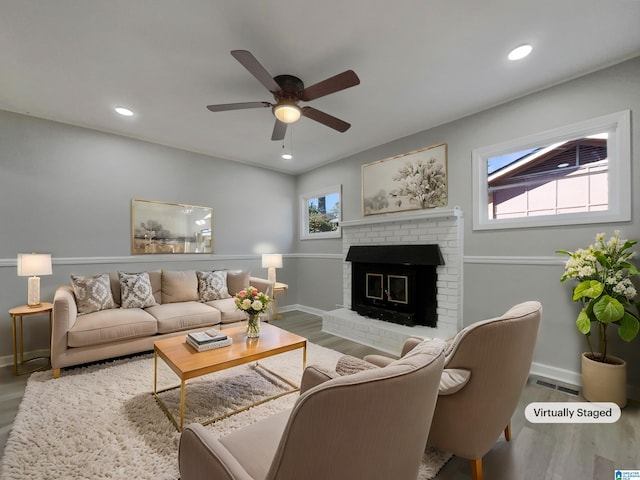 living area featuring a brick fireplace, wood finished floors, and recessed lighting