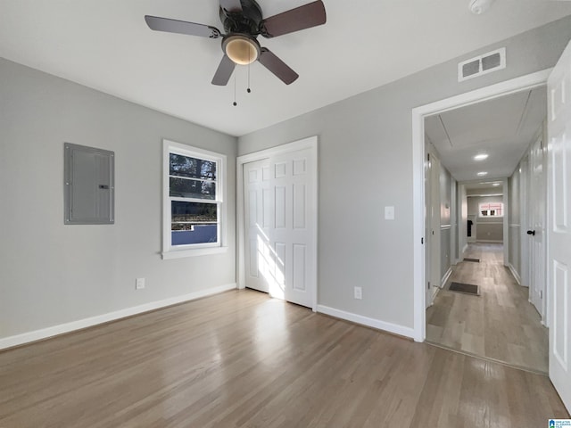 unfurnished bedroom with attic access, electric panel, baseboards, visible vents, and wood finished floors