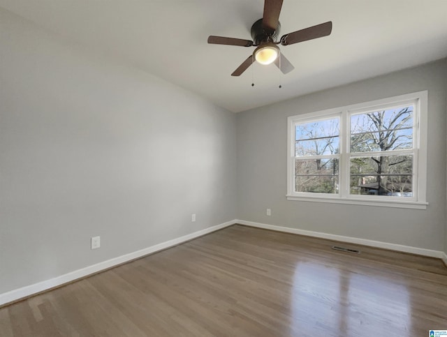 unfurnished room with wood finished floors, visible vents, and baseboards