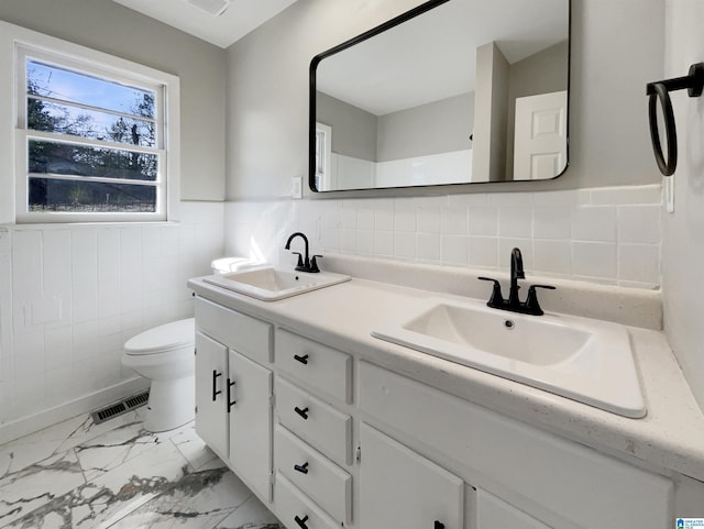 full bath featuring marble finish floor, wainscoting, a sink, and visible vents