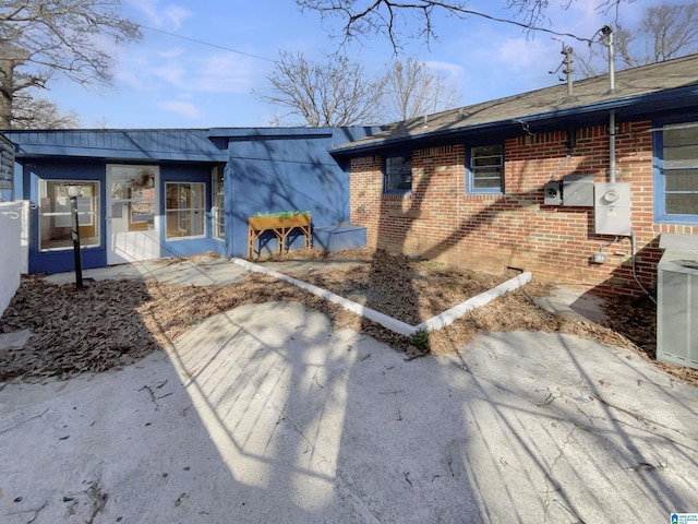 rear view of house with cooling unit and brick siding