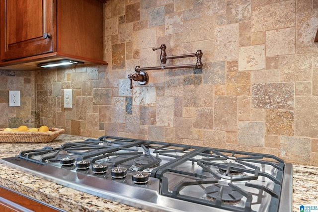 interior details with stainless steel gas cooktop, tasteful backsplash, and brown cabinets