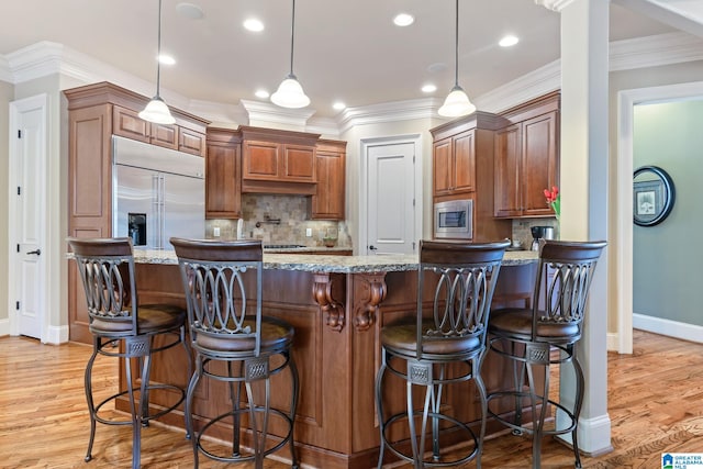 kitchen featuring built in appliances, light wood-style floors, ornamental molding, and light stone countertops