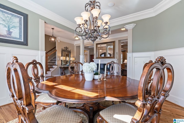 dining room featuring ornate columns, crown molding, stairway, and wood finished floors