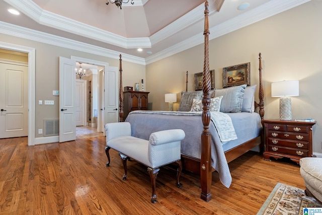 bedroom with a tray ceiling, visible vents, and light wood finished floors