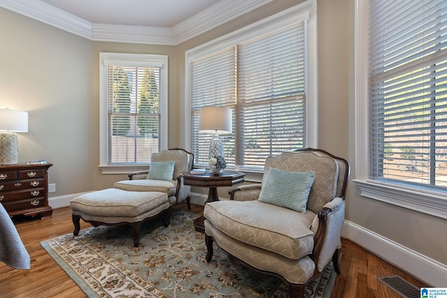 living area with ornamental molding, visible vents, baseboards, and wood finished floors