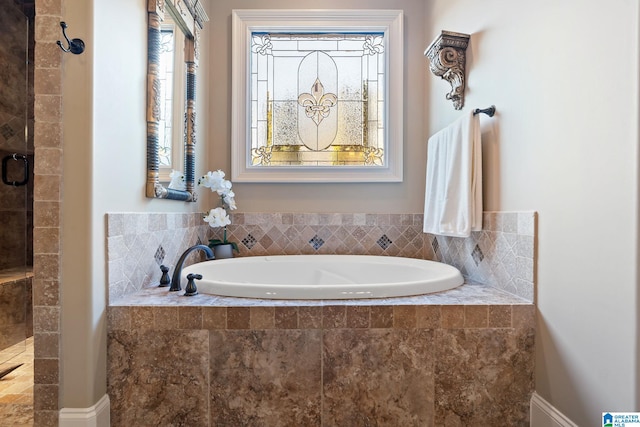 bathroom with a garden tub and tiled shower