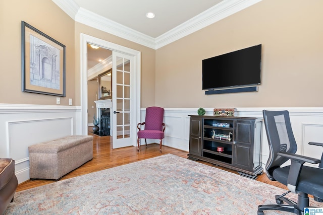 office featuring french doors, a decorative wall, ornamental molding, wainscoting, and wood finished floors