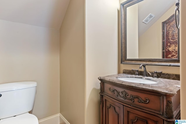 bathroom featuring lofted ceiling, toilet, vanity, visible vents, and baseboards