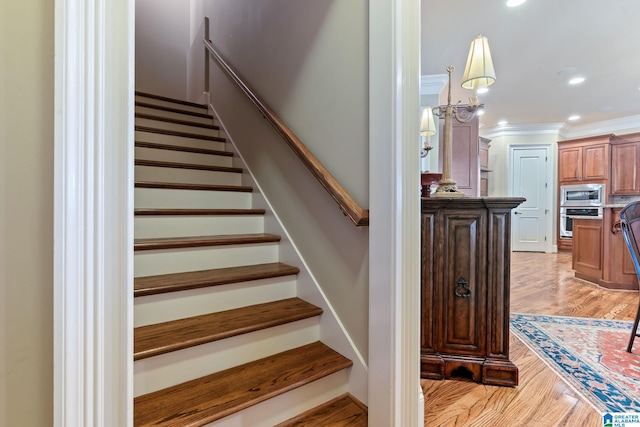 stairs featuring recessed lighting, crown molding, and wood finished floors