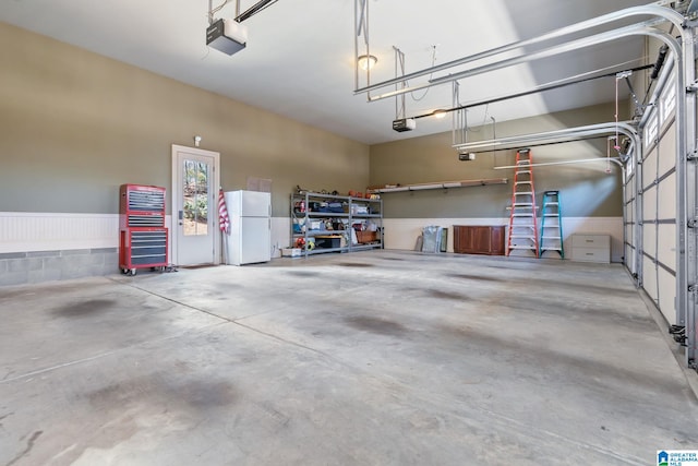 garage with a garage door opener and freestanding refrigerator