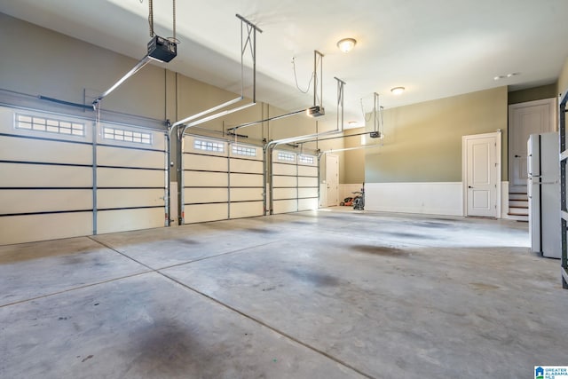 garage with a garage door opener and freestanding refrigerator