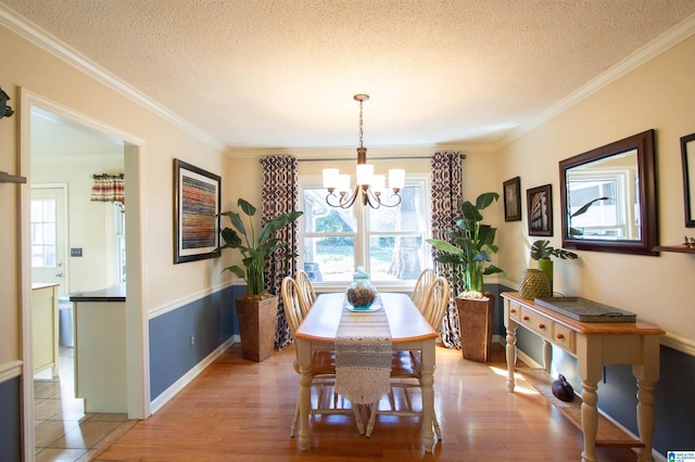 dining room with light wood-type flooring, an inviting chandelier, a textured ceiling, and crown molding