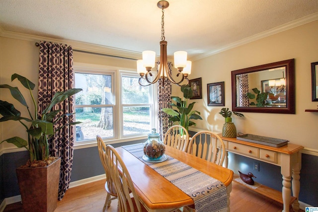 dining area featuring light wood-style floors, baseboards, a chandelier, and crown molding