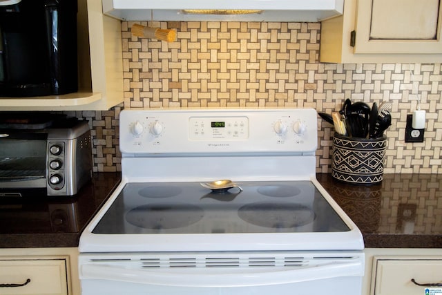 kitchen with dark countertops, a toaster, white cabinetry, and white electric range