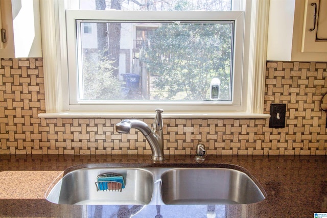 room details featuring tasteful backsplash, dark stone counters, and a sink