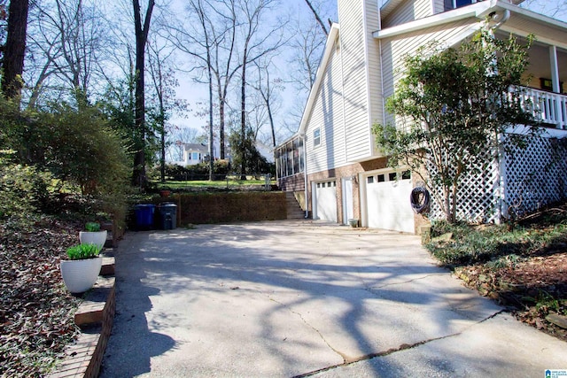 view of side of home with a garage, concrete driveway, and brick siding