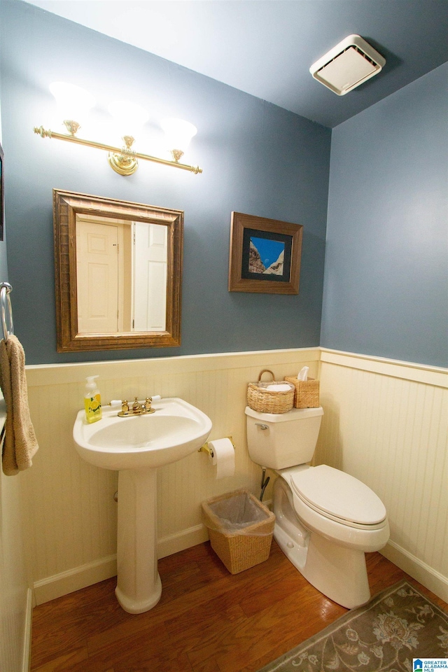 bathroom featuring toilet, wood finished floors, and wainscoting