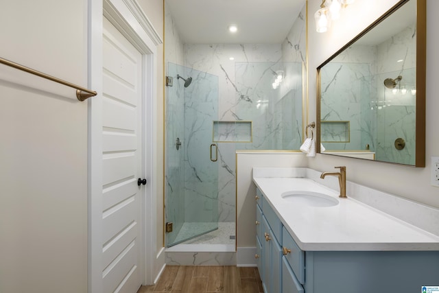 bathroom with wood finished floors, a marble finish shower, and vanity