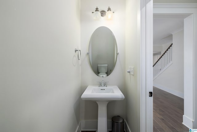 bathroom featuring baseboards, wood finished floors, and ornamental molding