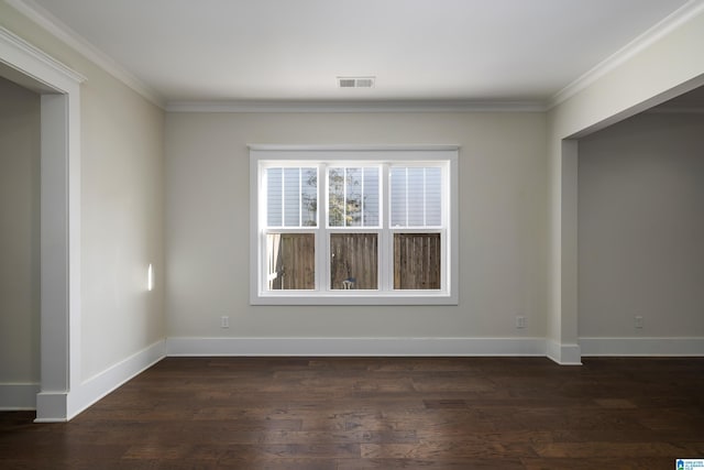 spare room with crown molding, visible vents, dark wood finished floors, and baseboards