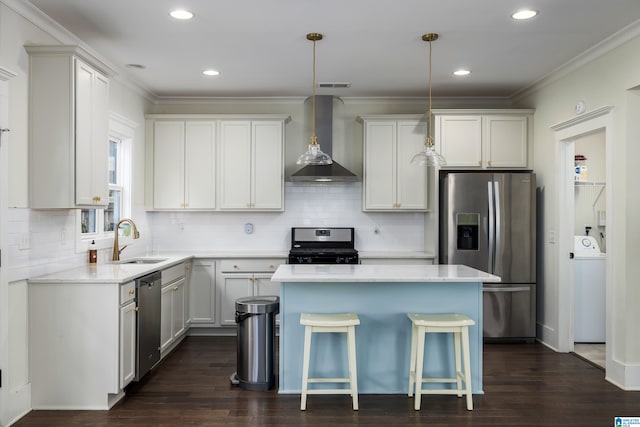 kitchen featuring stainless steel appliances, a sink, wall chimney range hood, a center island, and washer / clothes dryer