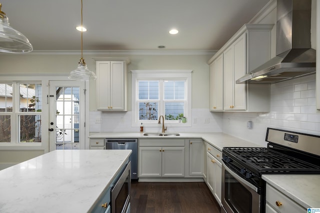 kitchen with dark wood finished floors, crown molding, appliances with stainless steel finishes, a sink, and wall chimney exhaust hood